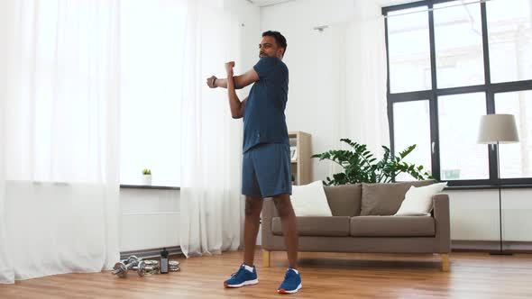 Man with Fitness Tracker Stretching Body at Home