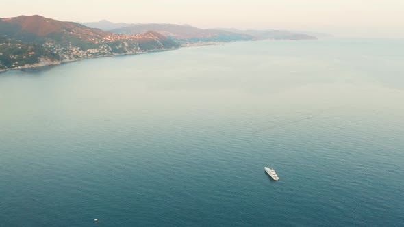 Aerial Footage of Mountains and Ligurian Sea with One White Boat at Sunset