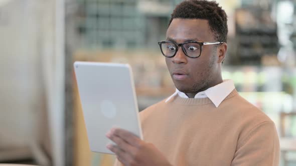 Successful Creative African Man Celebrating on Tablet in Cafe