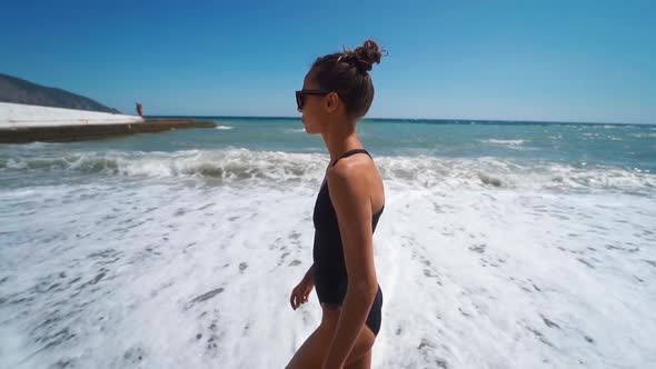 Camera Follows Happy Slim Woman in Swimwear Joyfully Running Into Waving Sea