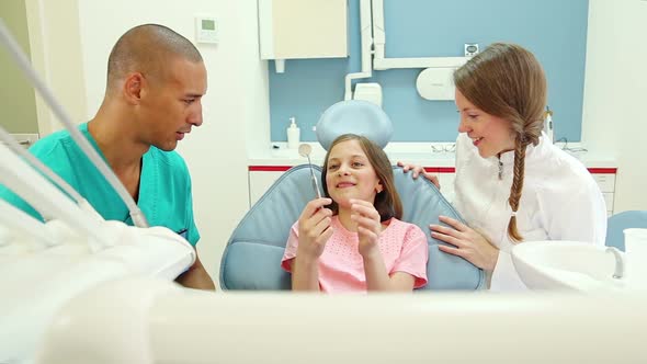 Dental assistant and dentist giving dental check up to little girl