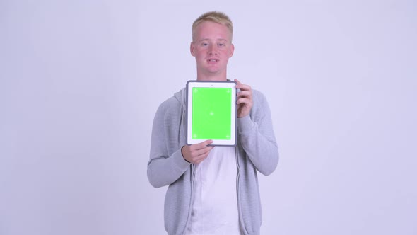 Happy Young Blonde Man Talking While Showing Digital Tablet