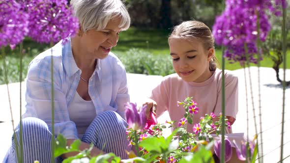 Grandmother and Girl Planting Flowers at Garden