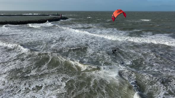 Kiteboarder showing his skills jumping in stormy sea with waves; aerial