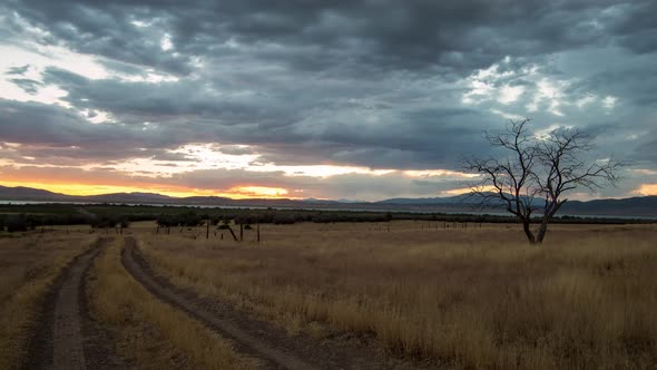 Time lapse of dirt road leading into sunset in dry grass land