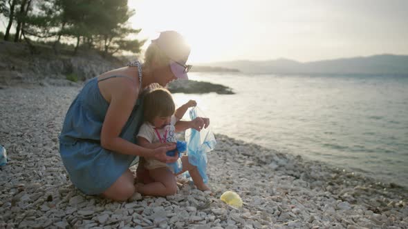 Girl Throws Plastic in the Trash on the Beach By the Sea