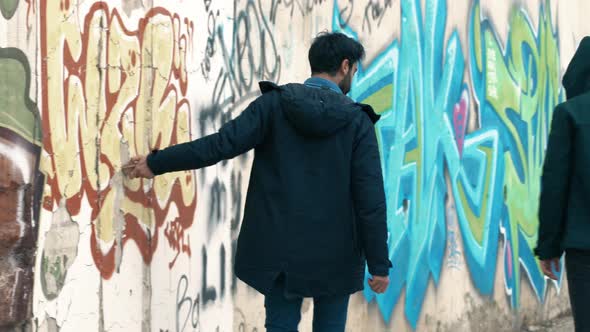 Drawing a graffiti painted wall with a stone.