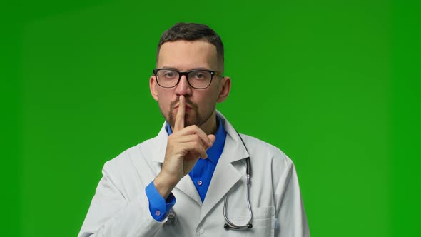 Handsome Young Man with Bear Wearing Doctor Uniform Asking to Be Quiet with Finger on Lips