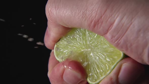 Man Hand Presses A Lime On A Black Background