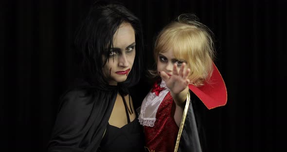 Woman and Child Dracula. Halloween Vampire Make-up. Kid with Blood on Her Face