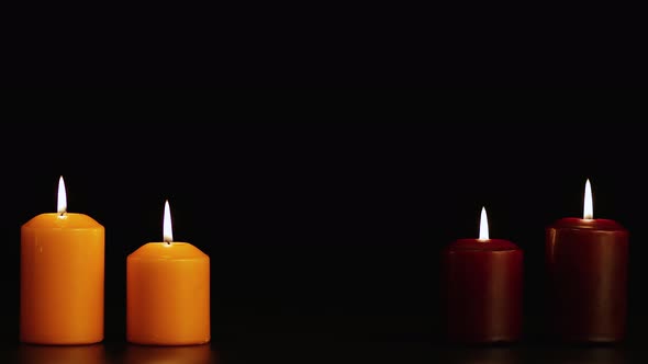 Four Beautifully Burning Candles on a Black Background in the Dark