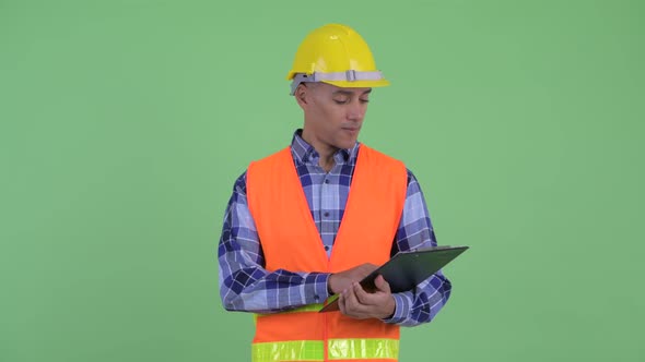 Happy Multi Ethnic Man Construction Worker Holding Clipboard and Pointing Finger