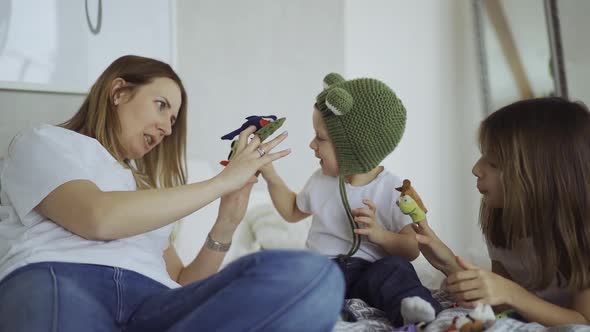 adorable mother and her children, daughter and little son play toys on fingers