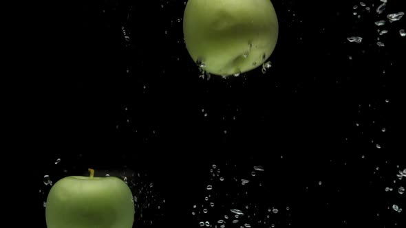 Slow Motion Three Green Apple Falling Into Transparent Water on Black Background