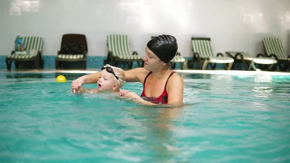 Young Mother is Teaching Her Little Cute Son to Swim in the Swimming Pool