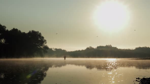 Fisherman pulling fish on the river in a foggy summer morning. Fishing for spinning.