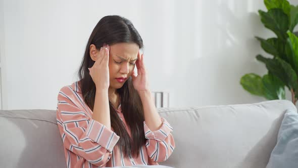 Asian beautiful upset depressed girl sitting alone on sofa in bedroom