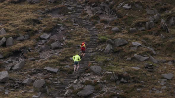 Mountain marathon runners on a cold and rainy day competing in a race in winter.