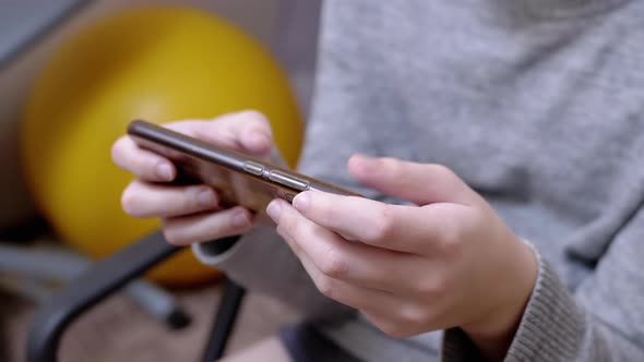 Child Sits in a Chair Holds a Smartphone in Hands Plays in Bedroom