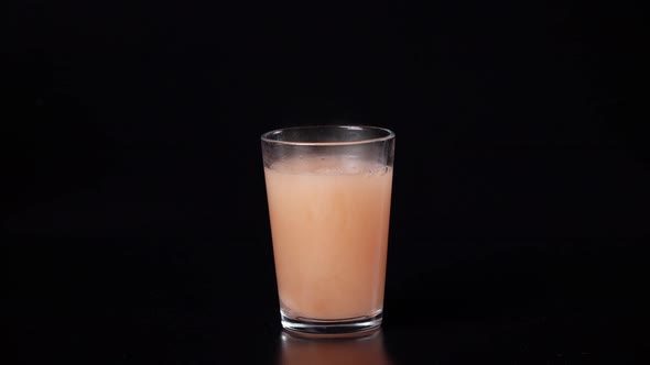 Effervescent Tablet in a Glass of Water Bubbles the Water Turns Colored on a Black Background