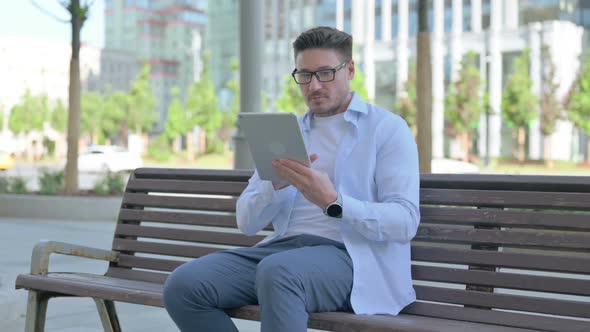 Man Using Tablet While Sitting Outdoor on Bench