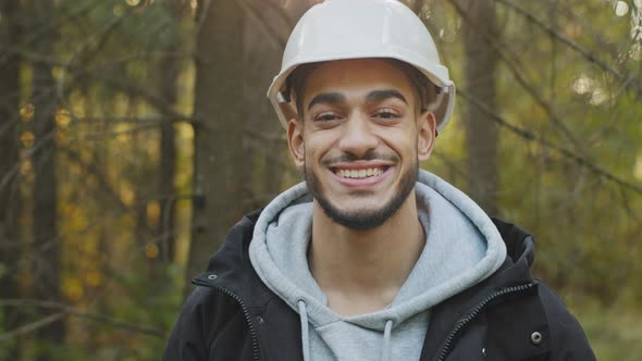 Male Portrait Young Smiling Hispanic Professional Worker in Safety Helmet Posing Outdoors Looking at