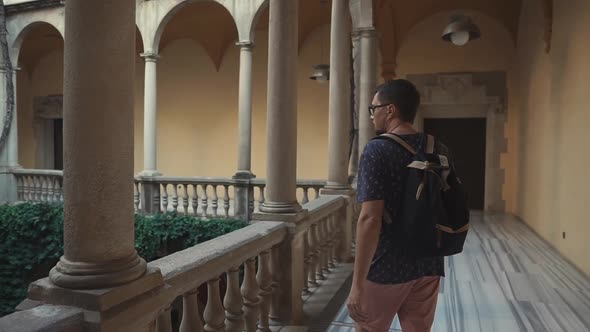 Male Traveler Is Examining Inner Yard and Balconies of Ancient European Palace