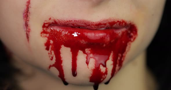 Bloody Mouth and Teeth of Girl. Vampire Halloween Makeup with Dripping Blood