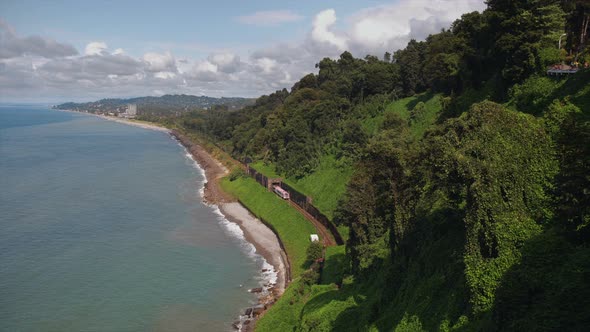 Mountains Covered Trees, Cliff To Beach Sea with Railway Tracks Tunnel, Train Moving, Garden on Hill