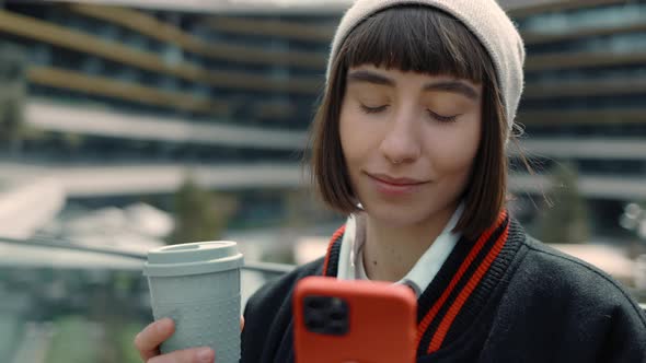 Woman Using Cell Phone and Drinking Coffee at Mall