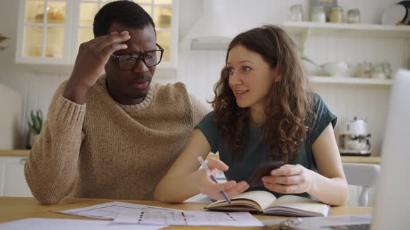 Multinational Couple Discuss Apartment Layout at Table