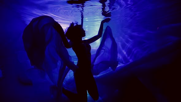 Silhouette of a Woman in the Dark Under the Water in a Long Dress Floating Pole Dancer