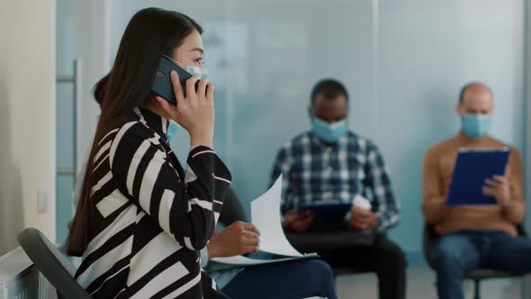 Asian Woman Talking on Phone Call and Waiting to Join Job Interview