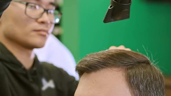 Barber Holds Tools in Hands Combs and Dries Dark Hair