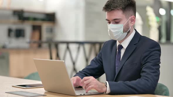 Young Businessman with Protective Face Mask Working on Laptop