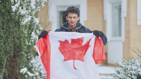 Portrait of Cheerful Handsome Middle Eastern Teen Boy Holding Canadian Flag Talking and Gesturing in