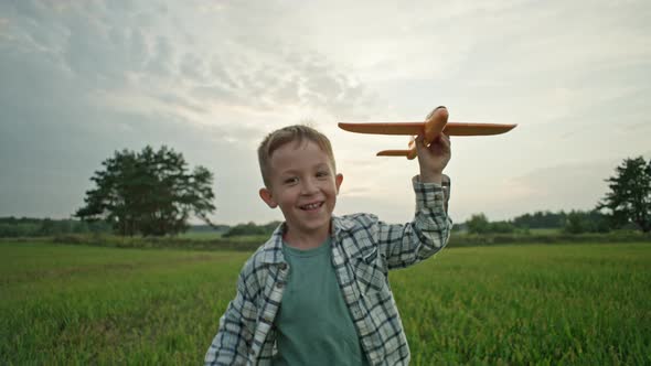 A Closeup of a Boy Who Runs with an Airplane in His Hands