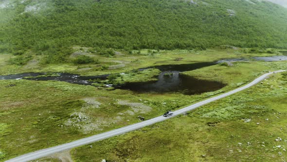 Car Driving On The Long And Winding Road Along The Lush Field And Calm Lake In Hydalen, A Hidden Gem