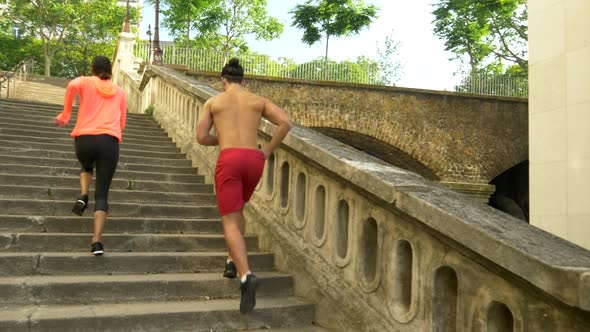 A couple running on stairs in a city as a workout