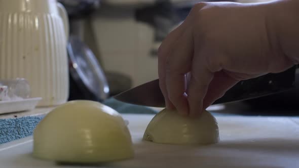 Adult Female Hands Slicing Onions On Chopping Board In Home Kitchen. Low Angle, Locked Off