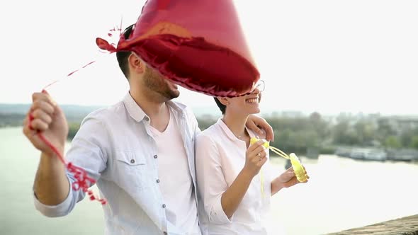 Romantic Young Couple Dating Outdoor and Blowing Bubbles