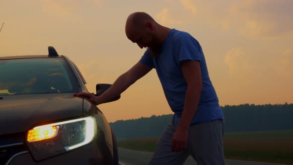 A Bald Bearded Man Stands By His Broken Car on the Side of the Road