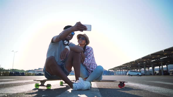 Young Mixed Race Hipster Doing Selfie Outdoors While Sitting on Longboards