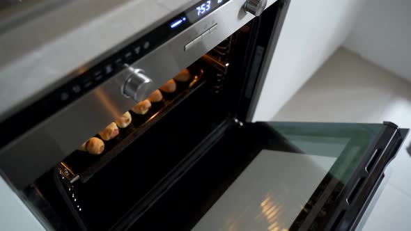 The Woman Opens the Oven Door and Takes Out a Baking Sheet with Pastries Hot Pies