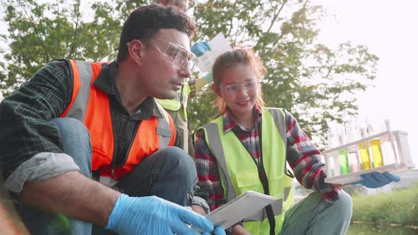 Scientist and assistants collecting samples of factory wastewater in a test tube