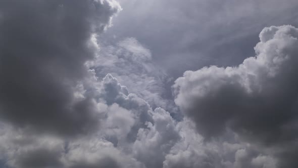 Time lapse of fast moving swirling afternoon storm clouds against a backlit blue sky