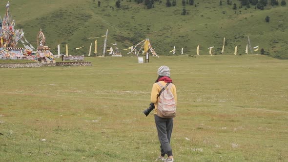 Female tourist with photo camera walking near flags and admiring landscape