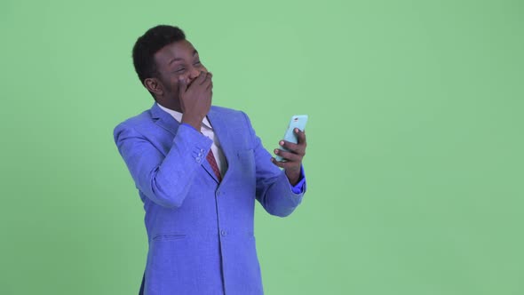 Happy Young African Businessman Using Phone and Looking Surprised