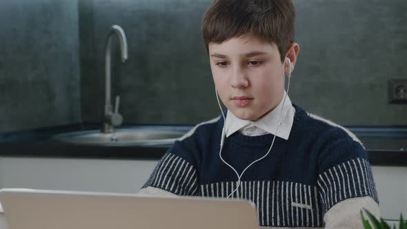 Portrait of Teenage Caucasian Boy Using Laptop While Studying at Home