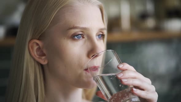 Young Woman Drinks Water From a Transparent Glass Closeup